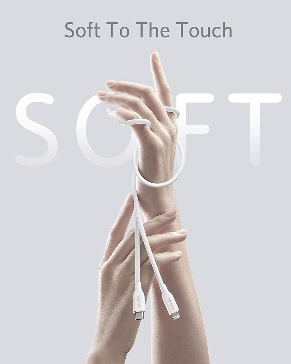 White charging cable being held between two hands with 'Soft To The Touch' text on a light gray background.