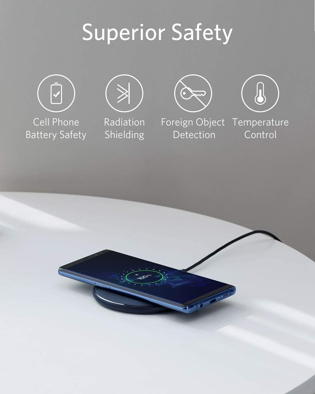 Wireless charging pad with smartphone on a white surface, featuring safety features text above.