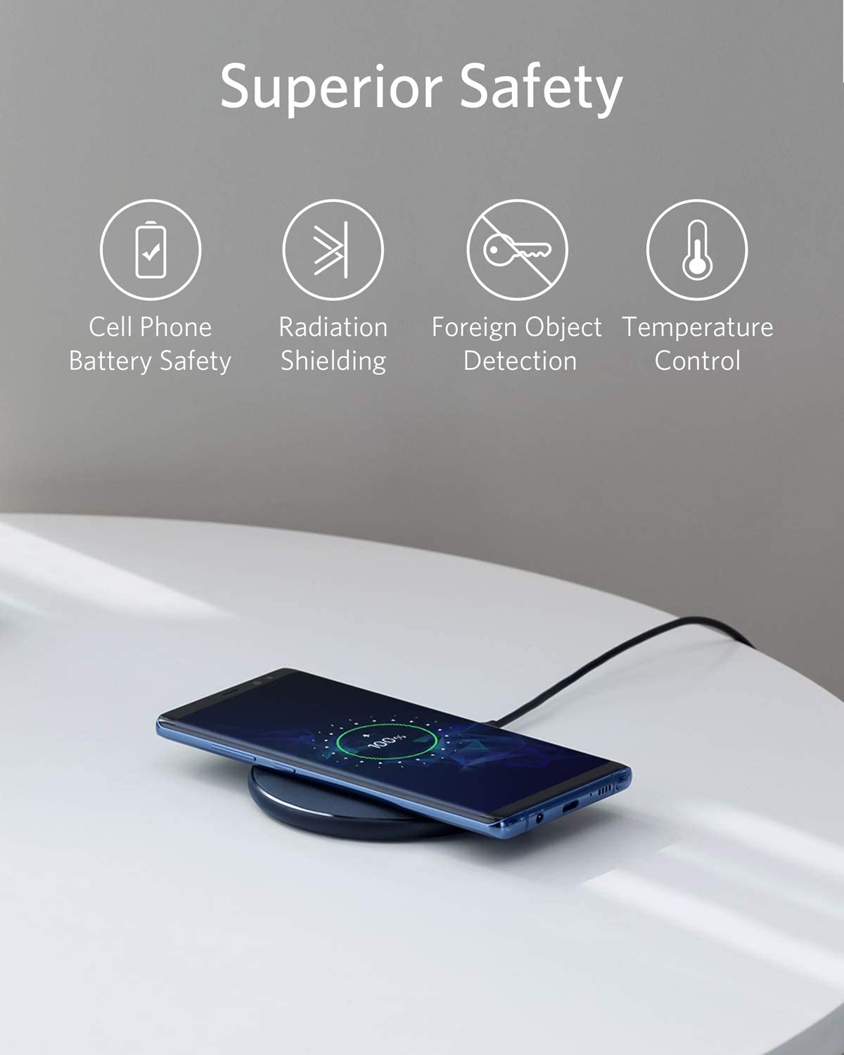 Wireless charging pad with smartphone on a white surface, featuring safety features text above.