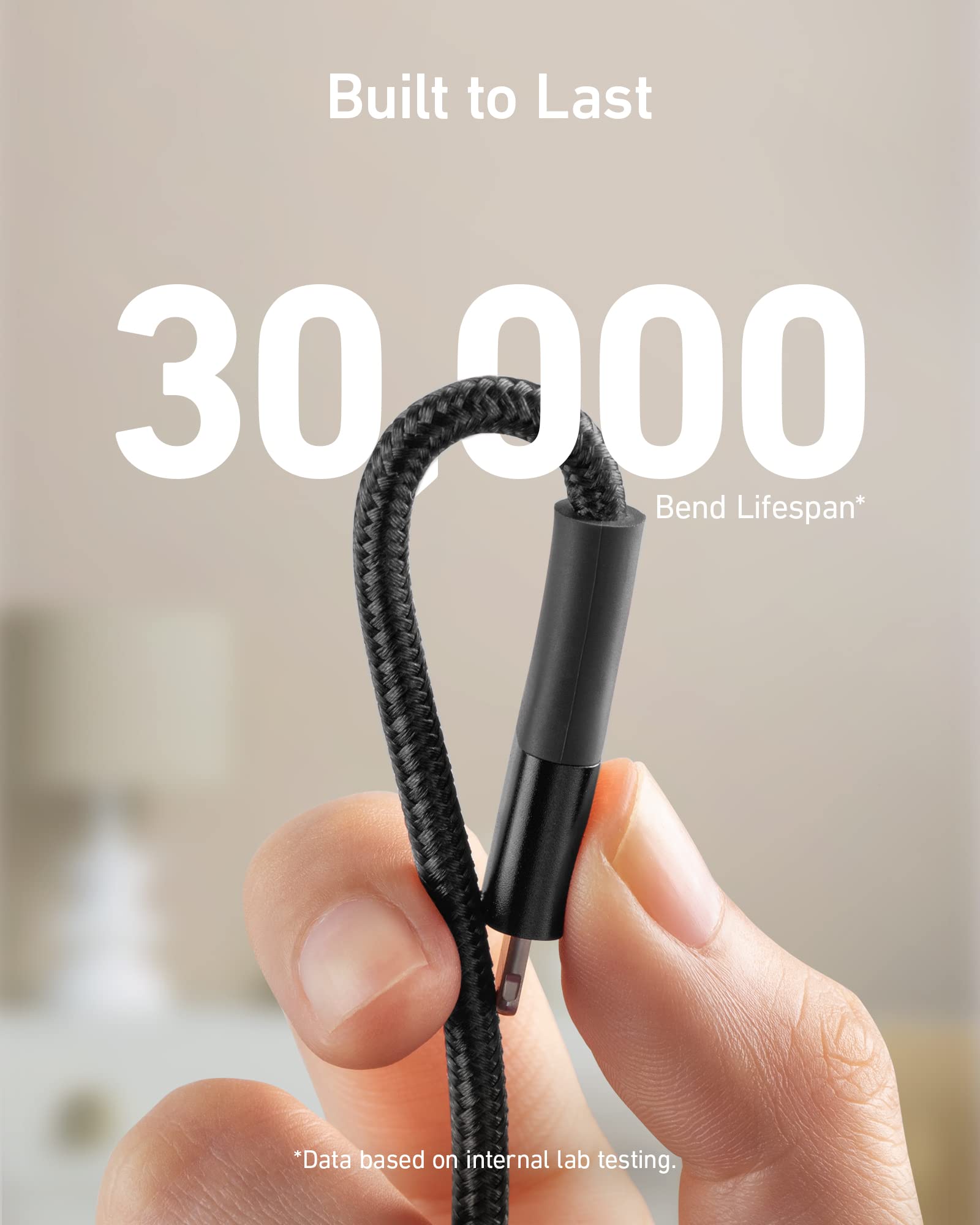 Hand holding a black cable with '30,000 Bend Lifespan' text on a blurred background