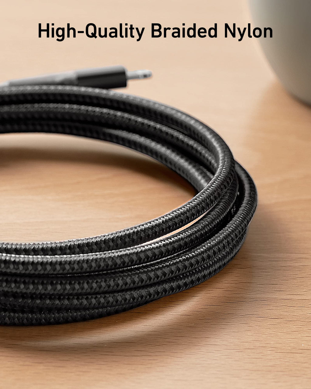 Coiled black high-quality braided nylon cable on a wooden surface with text overlay.