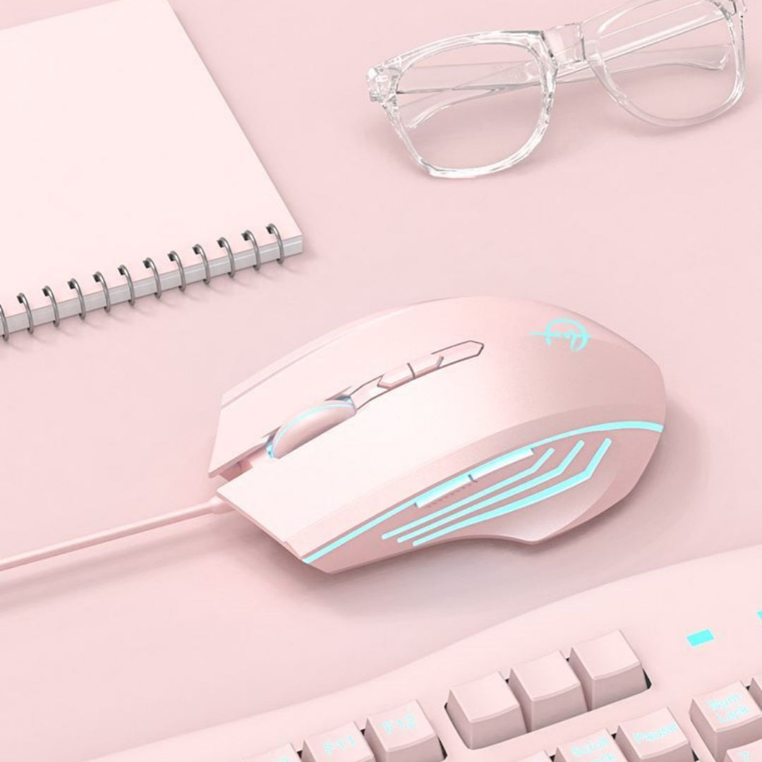 Pink gaming mouse with blue lighting on a pink surface with a notebook and glasses.