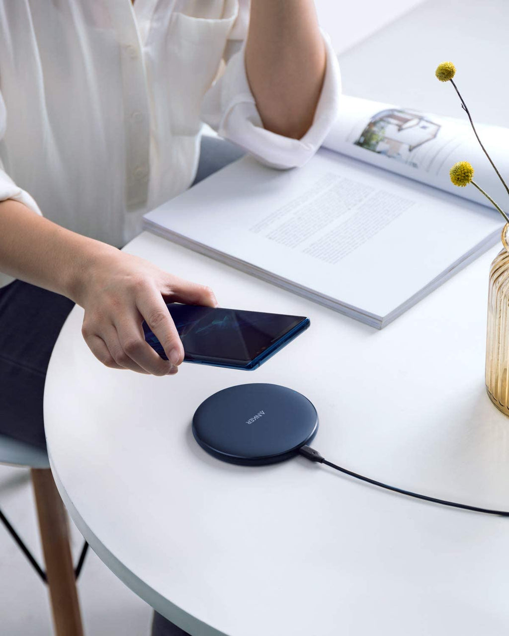 Person using a wireless charging pad on a table with a smartphone