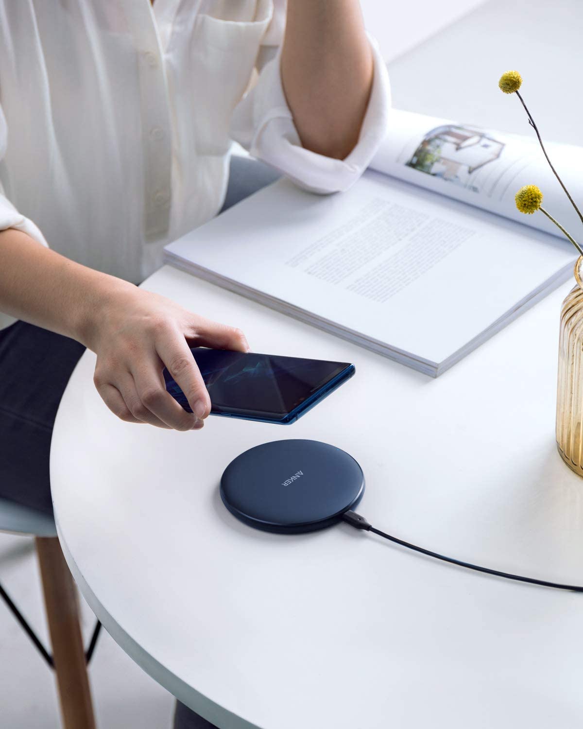 Person using a wireless charging pad on a table with a smartphone