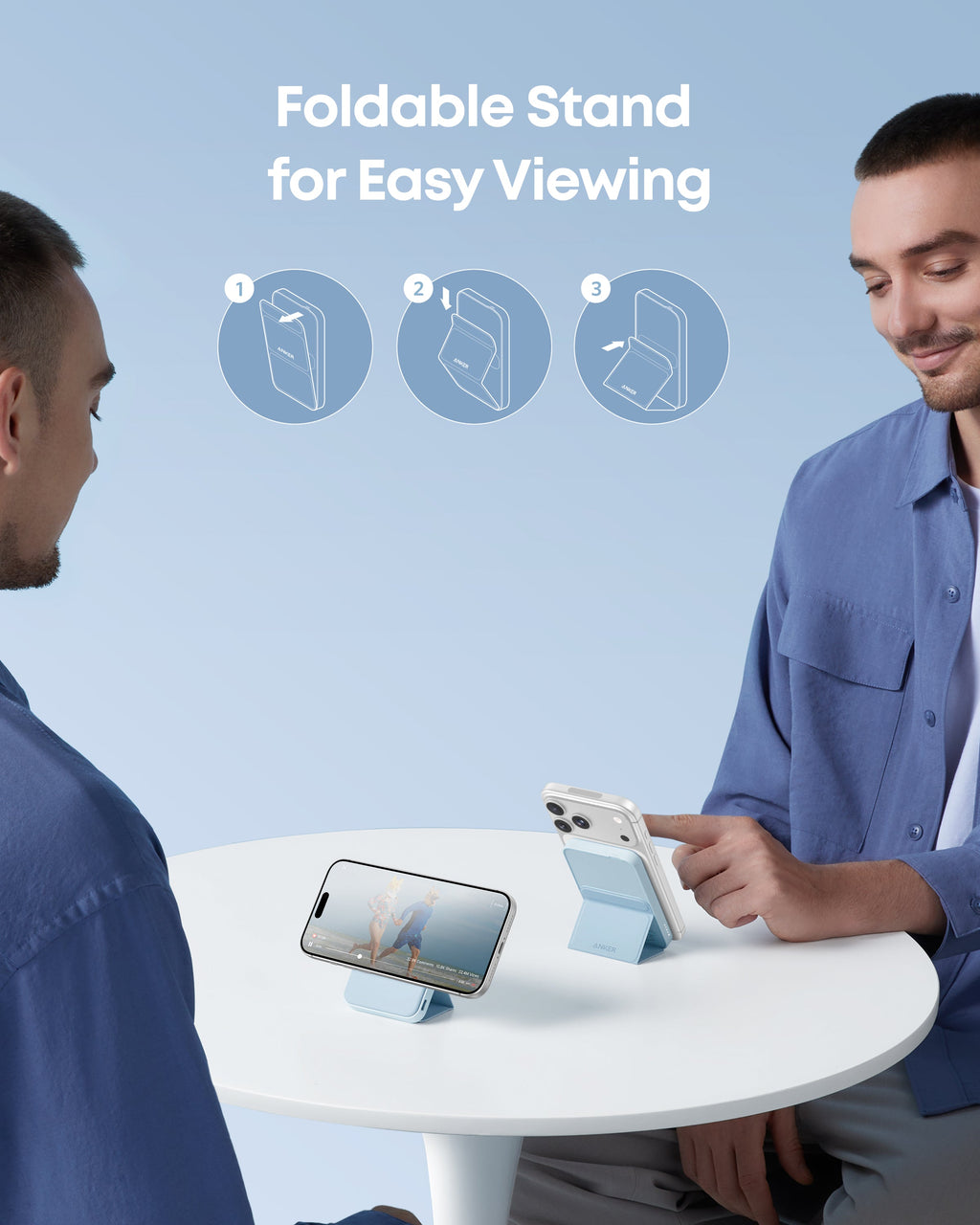 Two men using a foldable stand for easy viewing of a smartphone on a table.