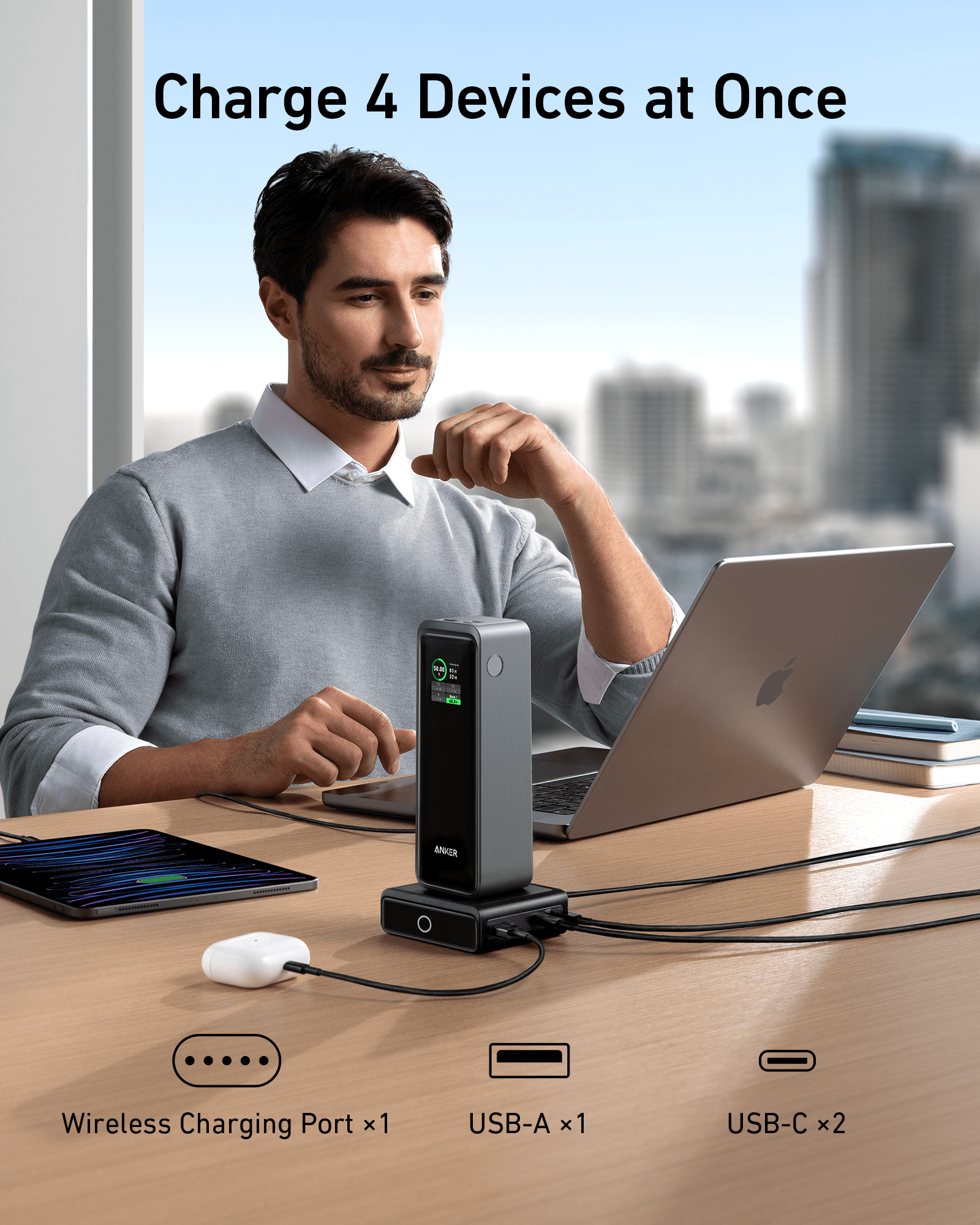 Man using a multi-device charging station with laptop, tablet, and earbuds in an office setting.