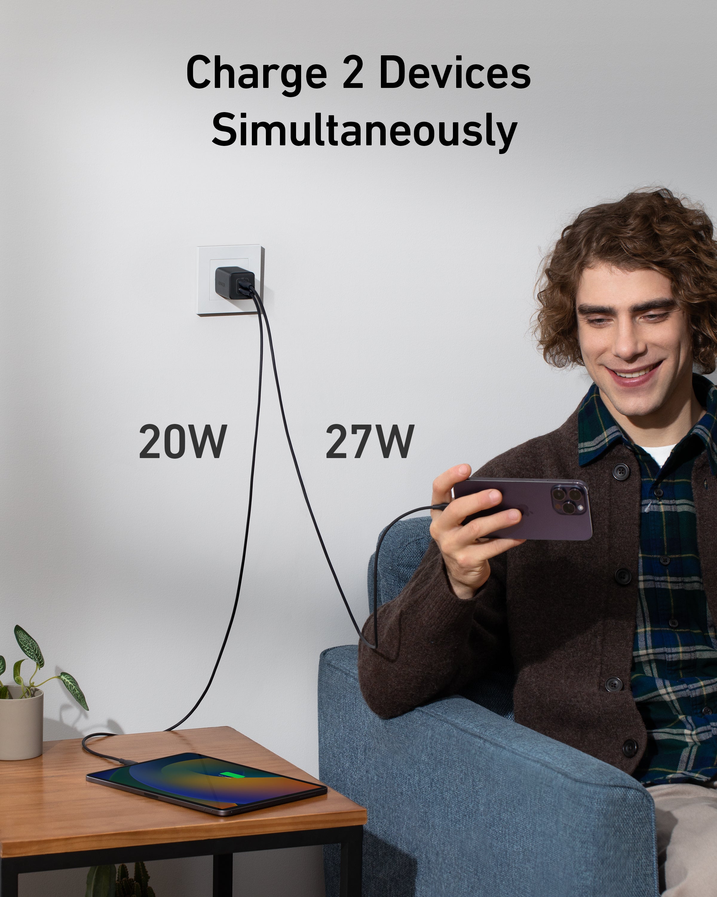 Person sitting on a couch using a smartphone with text indicating simultaneous charging of two devices.