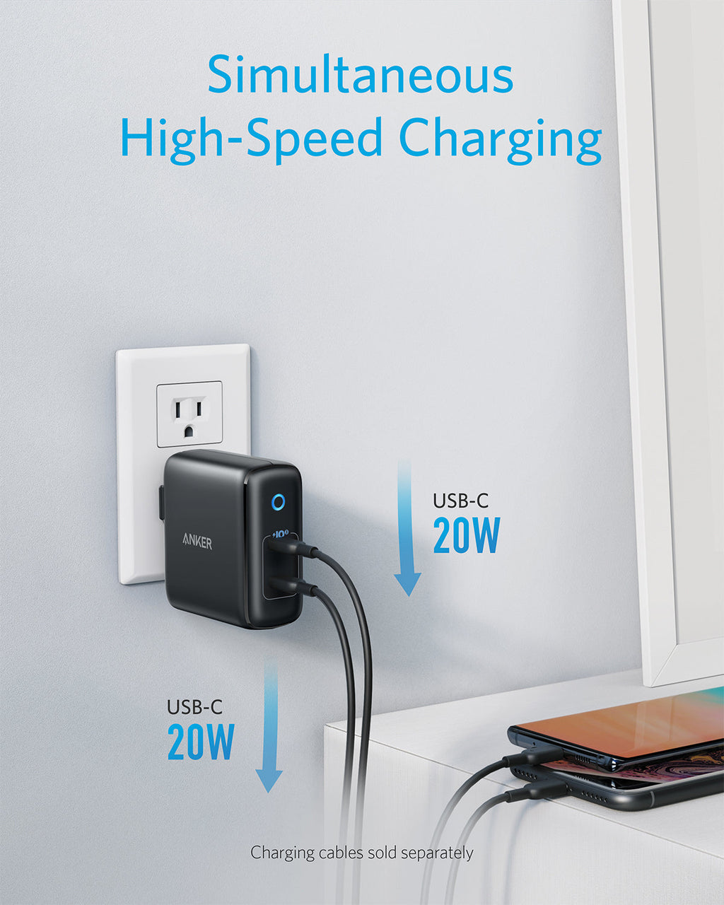 Anker power adapter with two USB-C ports charging devices on a white surface.