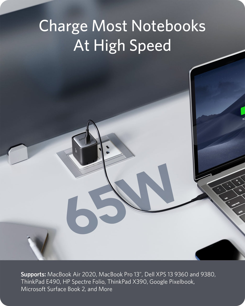 Laptop being charged with a 65W power adapter on a desk.