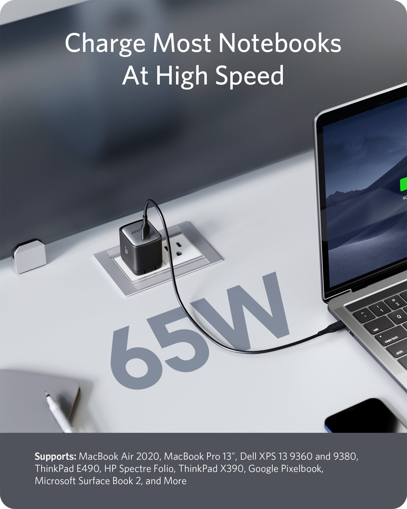 Laptop being charged with a 65W power adapter on a desk.