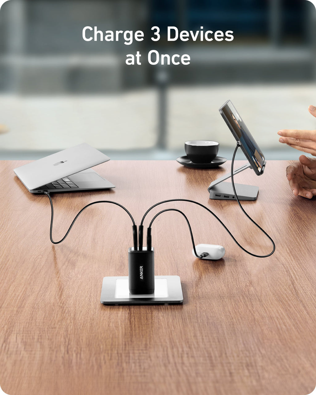 USB hub charging three devices on a desk with a blurred office background