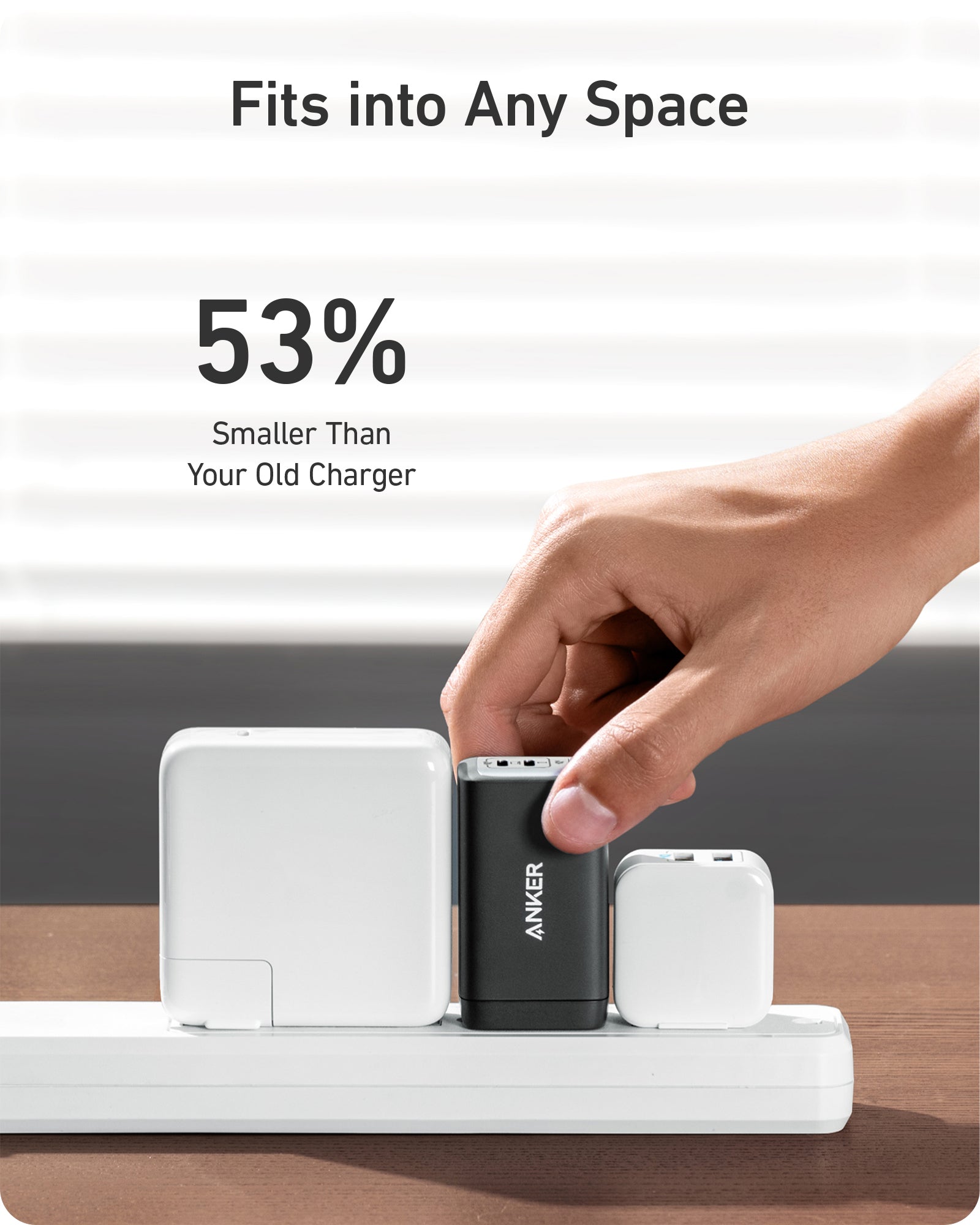 Hand placing a small Anker charger into a charging station with text indicating it's 53% smaller than an old charger.
