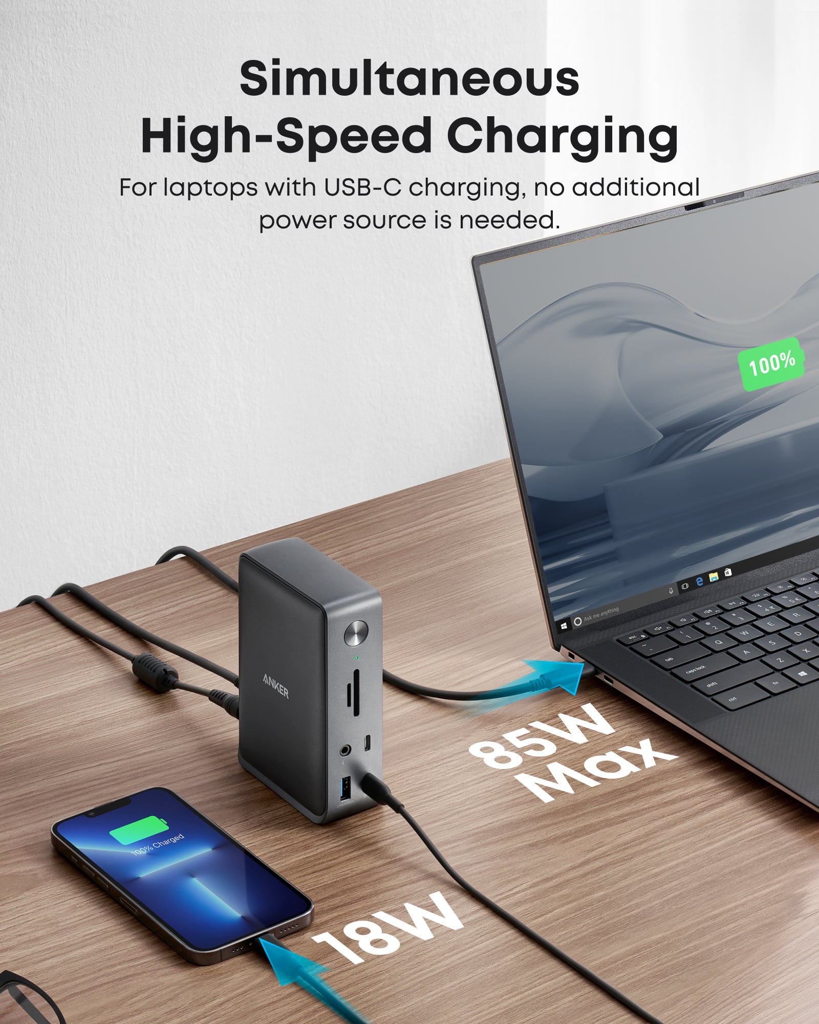 Laptop and smartphone being charged simultaneously with a power adapter on a wooden surface.