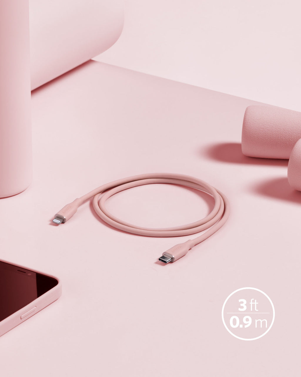 Pink charging cable on a pink surface with a smartphone and headphones.