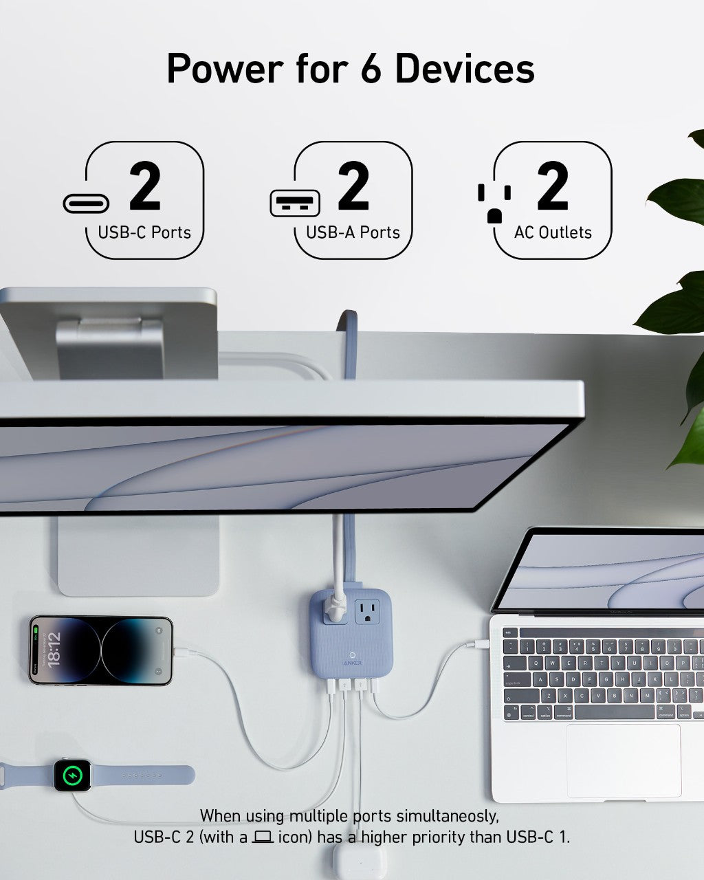 Desk setup with multiple devices connected to a power hub, showcasing USB-C, USB-A, and AC outlet ports.