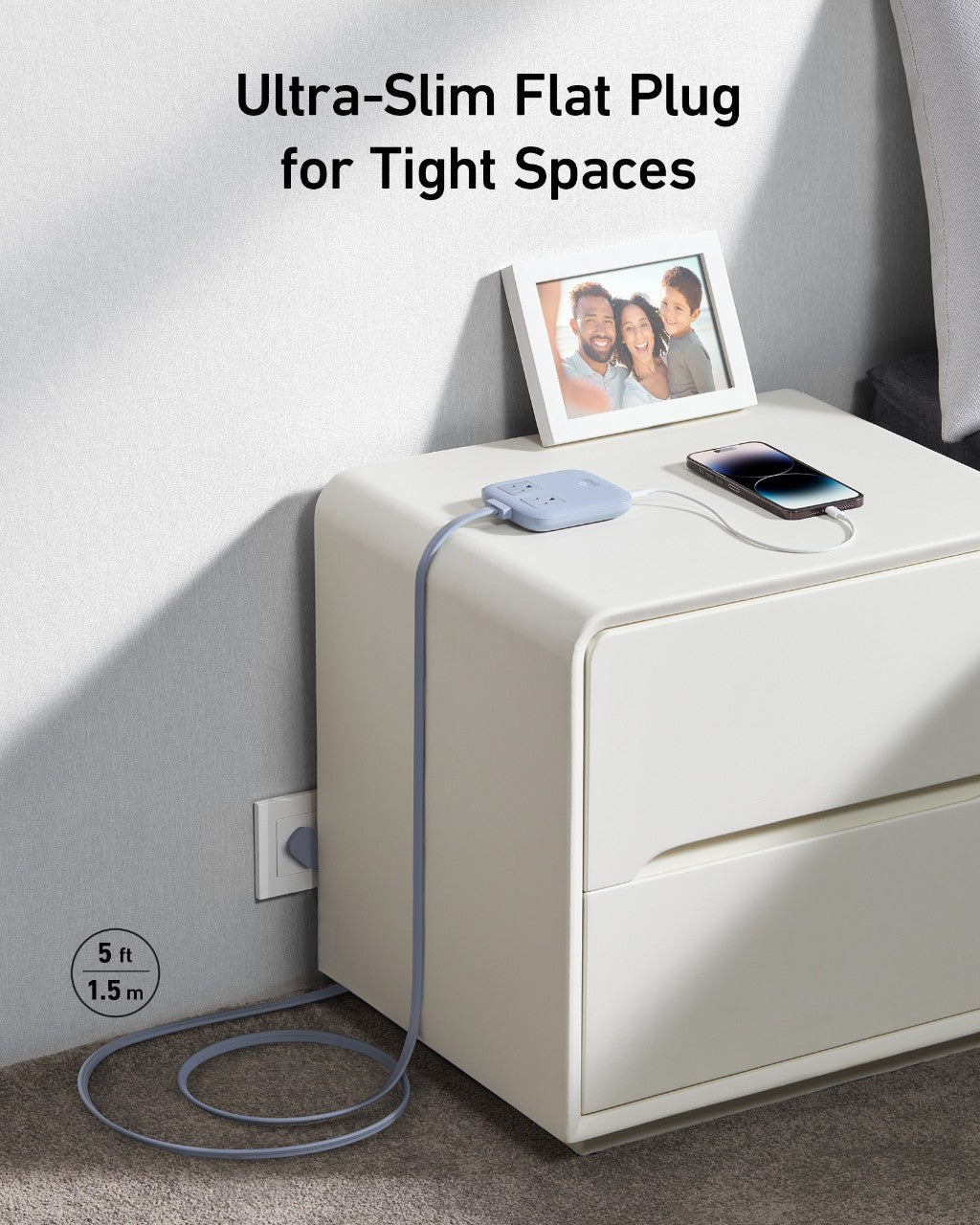 Ultra-slim flat plug for tight spaces with a white nightstand and electronic devices.