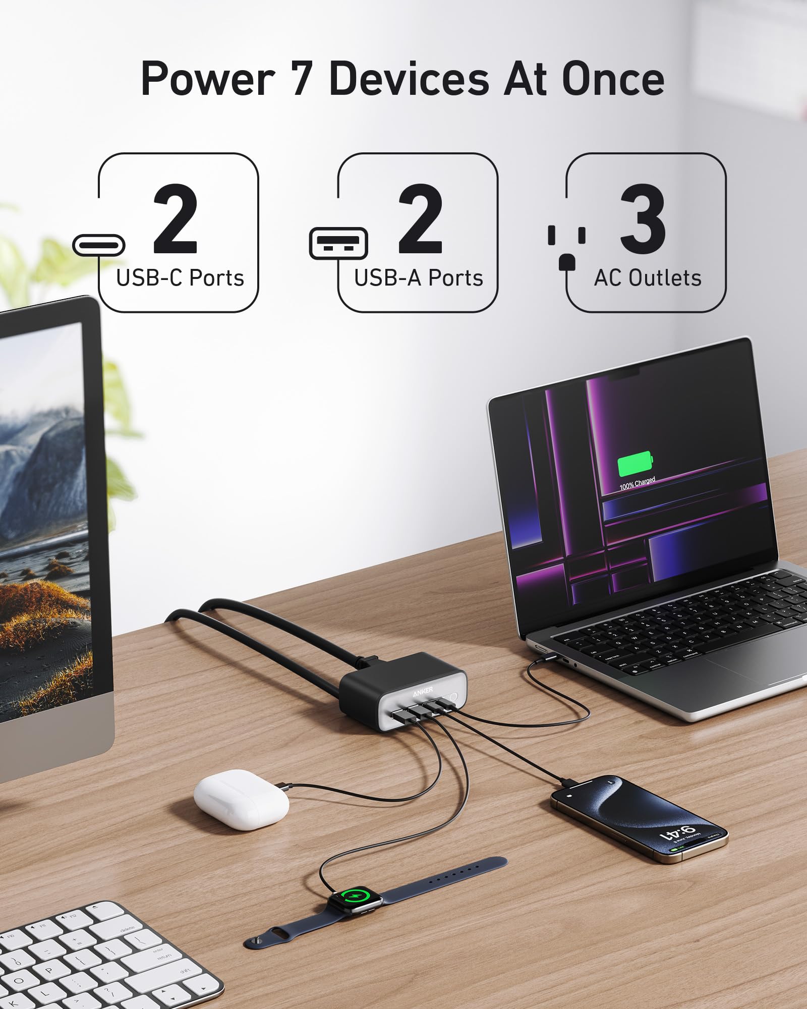 Desk setup with a laptop, monitor, mouse, keyboard, and phone connected to a power adapter, highlighting multiple ports.