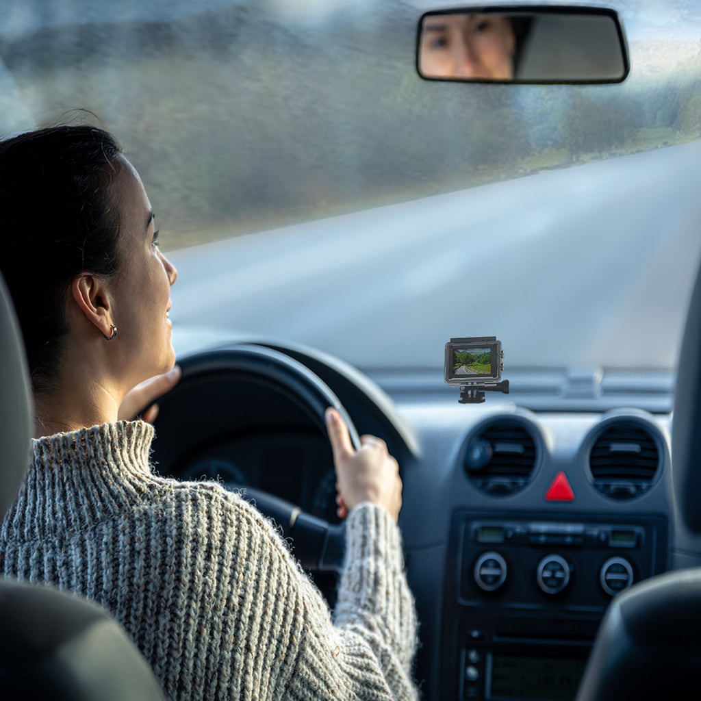 Woman driving a car with a small screen device on the dashboard.