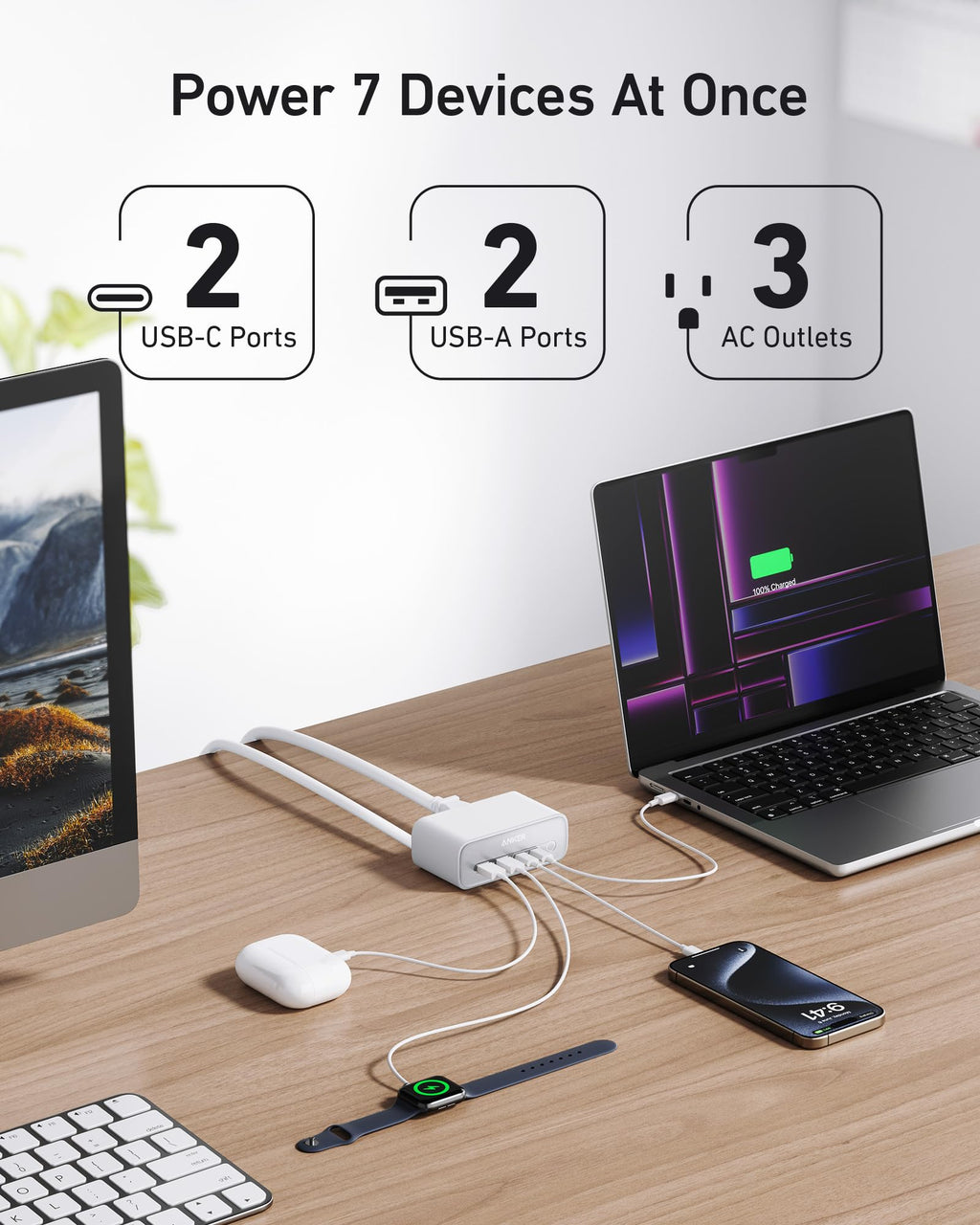 Desk setup with a laptop, monitor, phone, and keyboard connected to a power adapter with multiple ports.