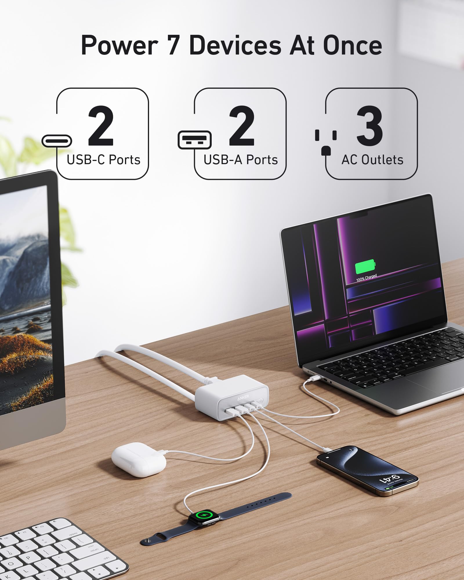 Desk setup with a laptop, monitor, phone, and keyboard connected to a power adapter with multiple ports.