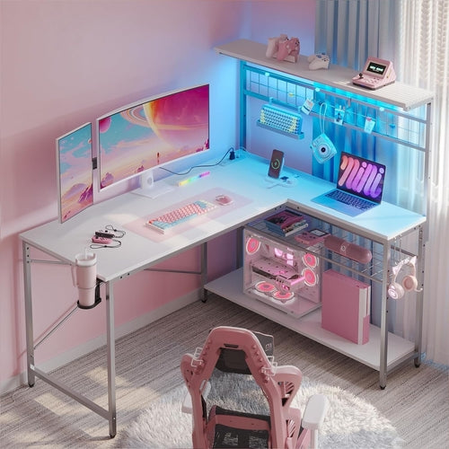 Modern gaming desk setup with multiple monitors, a laptop, and gaming accessories in a room with pink walls.