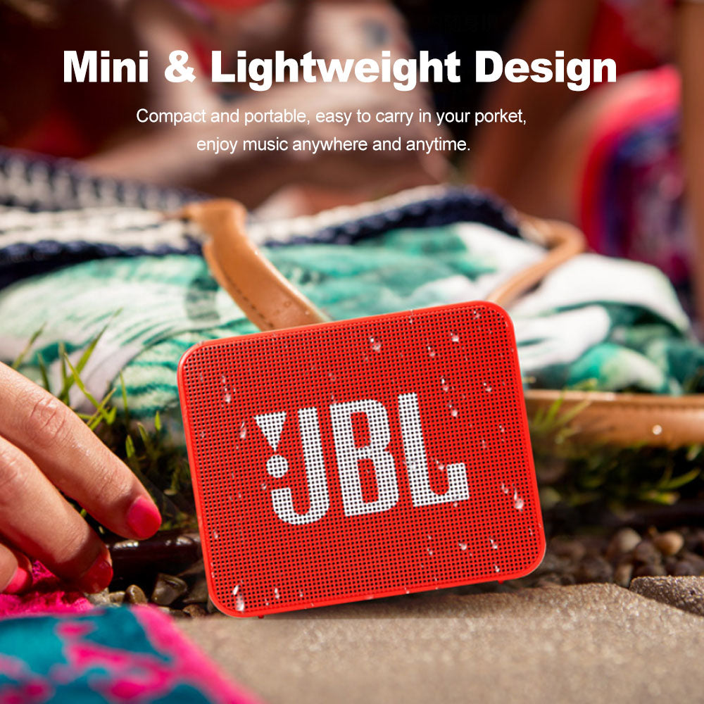 Red JBL speaker on a grassy surface with text highlighting its mini and lightweight design.